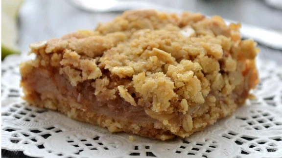 A close-up of a slice of apple crisp with an oatmeal crumble topping