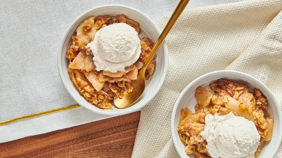 Apple crisp dessert with vanilla ice cream served in white bowls