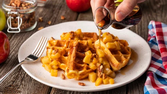Waffles topped with caramelized apples, syrup, and pecans