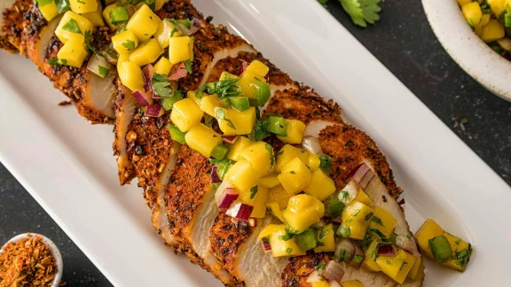 Grilled chicken breast topped with mango salsa on white platter