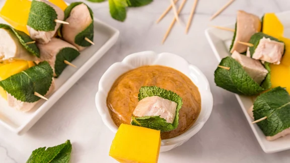 Chicken and mango skewers wrapped in mint leaves with dipping sauce