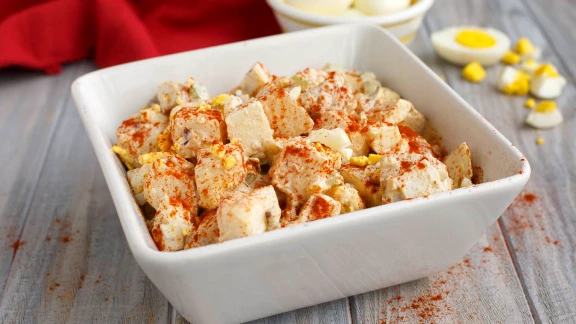Potato salad with egg and paprika in a white bowl