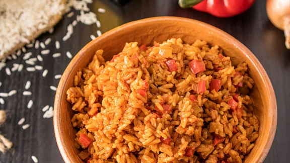 Mexican-style rice with red bell peppers and seasoned spices served in wooden bowl