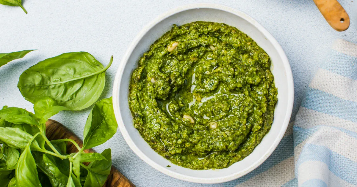 Bowl of basil pesto with fresh basil leaves