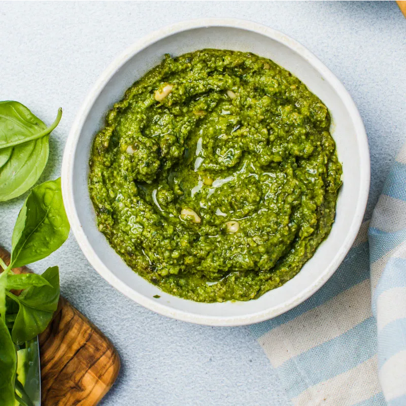 Bowl of basil pesto with fresh basil leaves