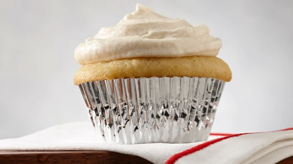 Vanilla cupcake with frosting in a foil liner