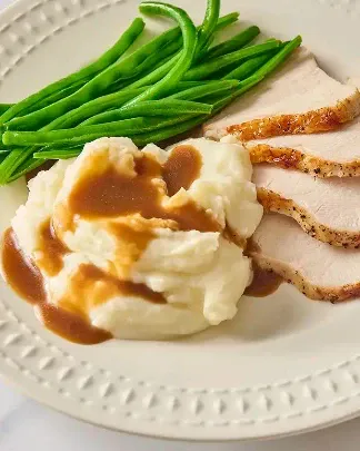 Sliced roast turkey with mashed potatoes and green beans